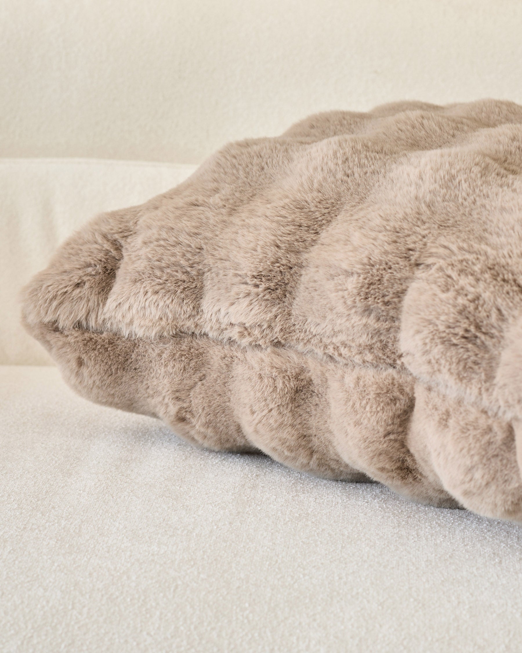 Large taupe cushion with gathered ruched texture and soft plush fabric, displayed at an angle on neutral background.
