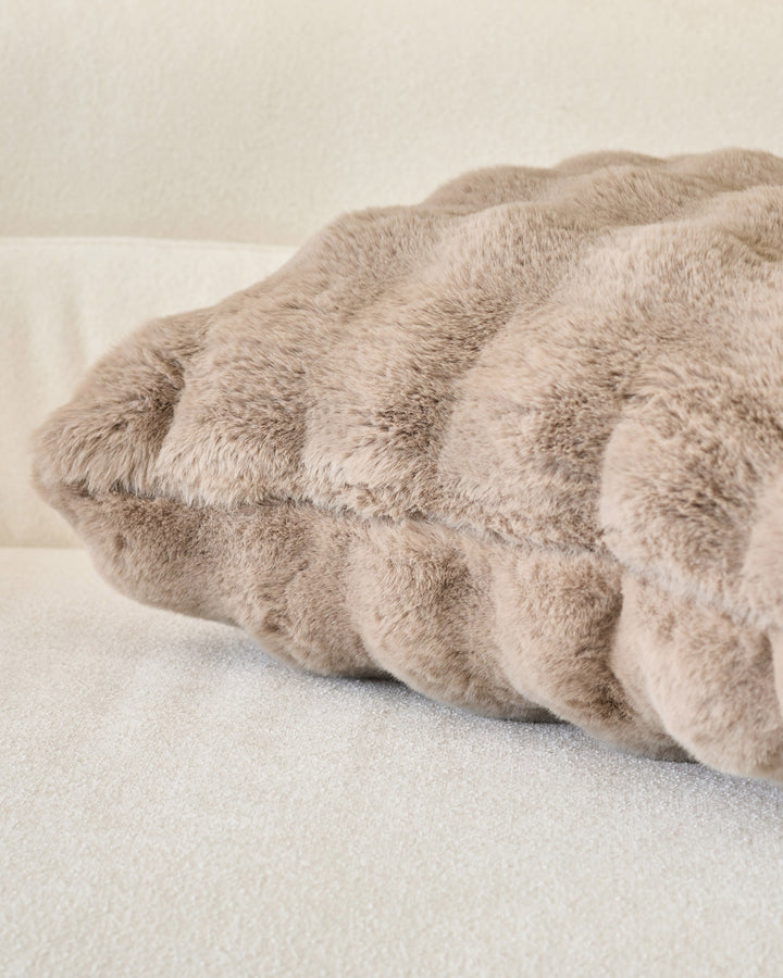Large taupe cushion with gathered ruched texture and soft plush fabric, displayed at an angle on neutral background.