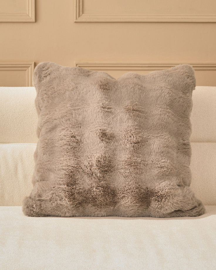 Large taupe plush cushion with quilted diamond pattern, displayed on a cream upholstered sofa against a beige paneled wall.