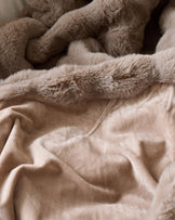 Nova throw blanket in taupe, close-up showing soft plush texture layered over smooth cotton fabric.