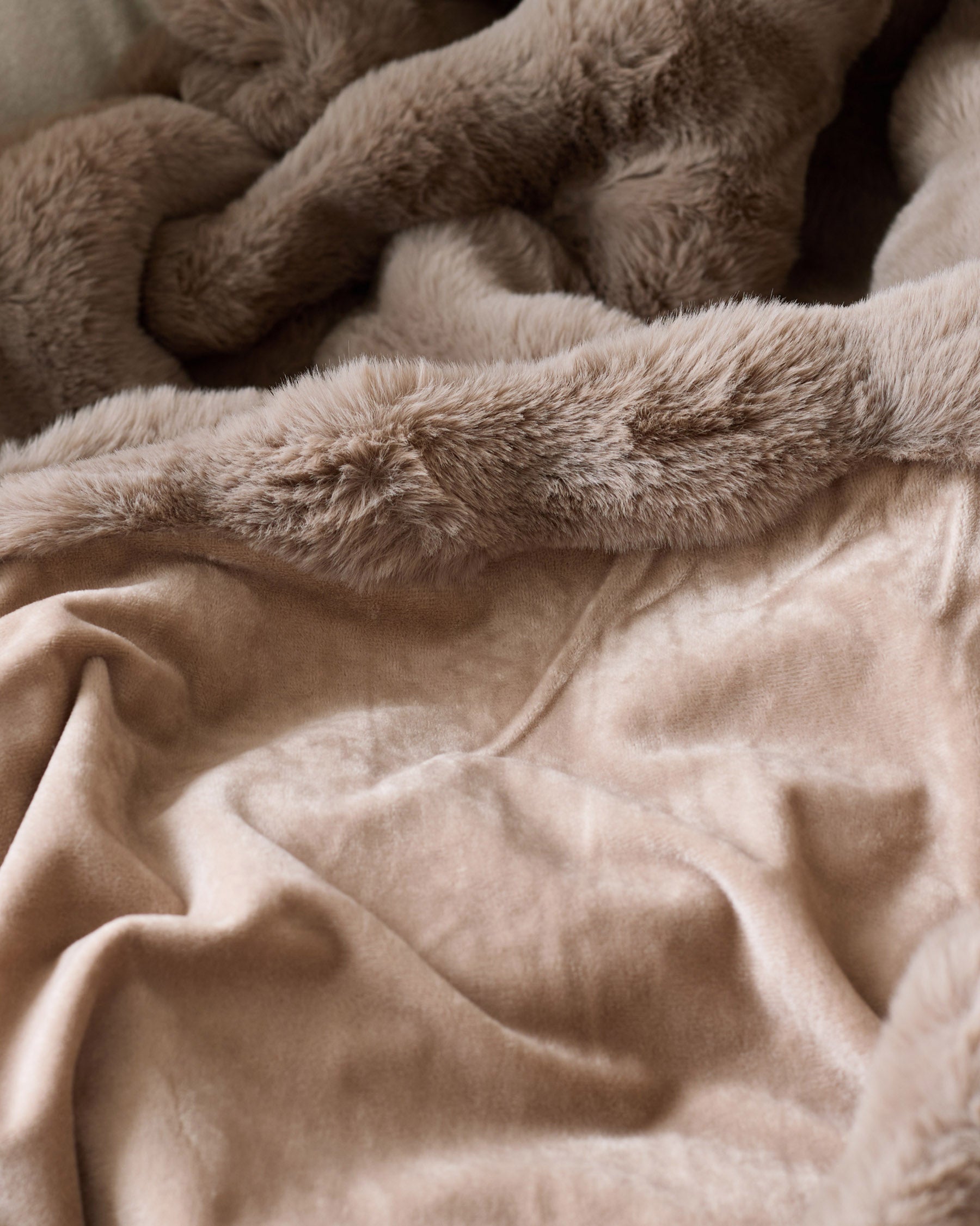 Nova throw blanket in taupe, close-up showing soft plush texture layered over smooth cotton fabric.