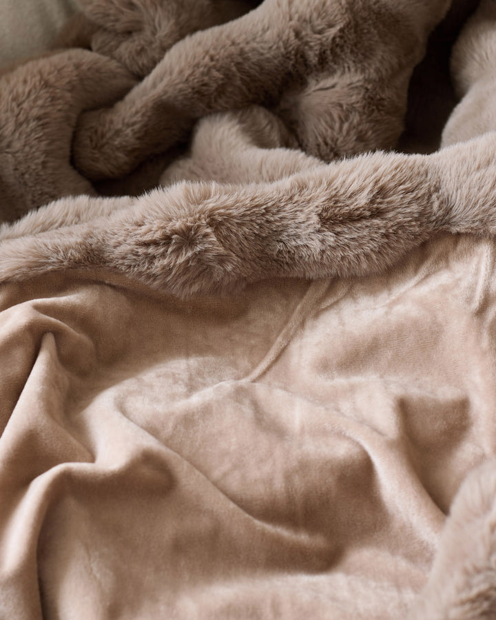 Nova throw blanket in taupe, close-up showing soft plush texture layered over smooth cotton fabric.
