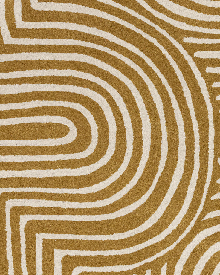 Abstract swirl medium sculpted wool rug in ochre and cream with raised textured pile detail.