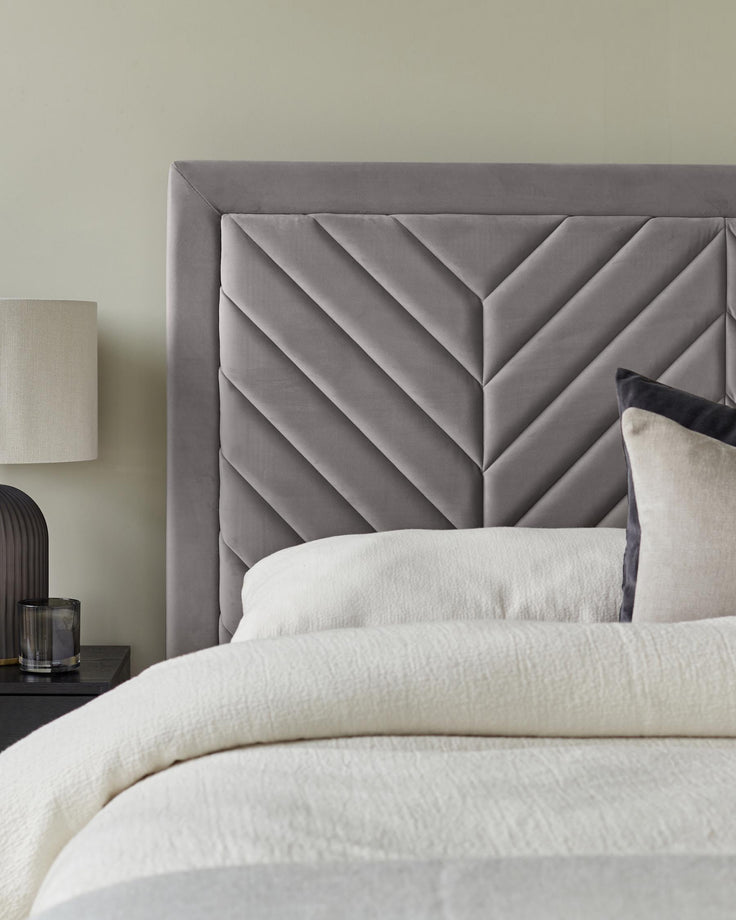 A stylish grey chevron headboard, with a cosy bed and bedside table, perfect for a modern bedroom.