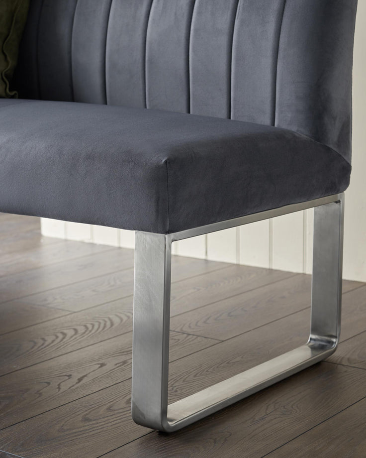 Close-up of a grey upholstered bench with a sleek, minimalist metal leg design, showcasing modern furniture craftsmanship.