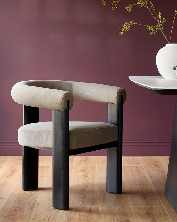 A stylish modern chair with a curved back and a dark wood frame, next to a table with a white top.