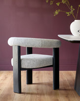 Stylish chair with grey tweed upholstery and dark wood legs. Sleek table with white top and dark base.