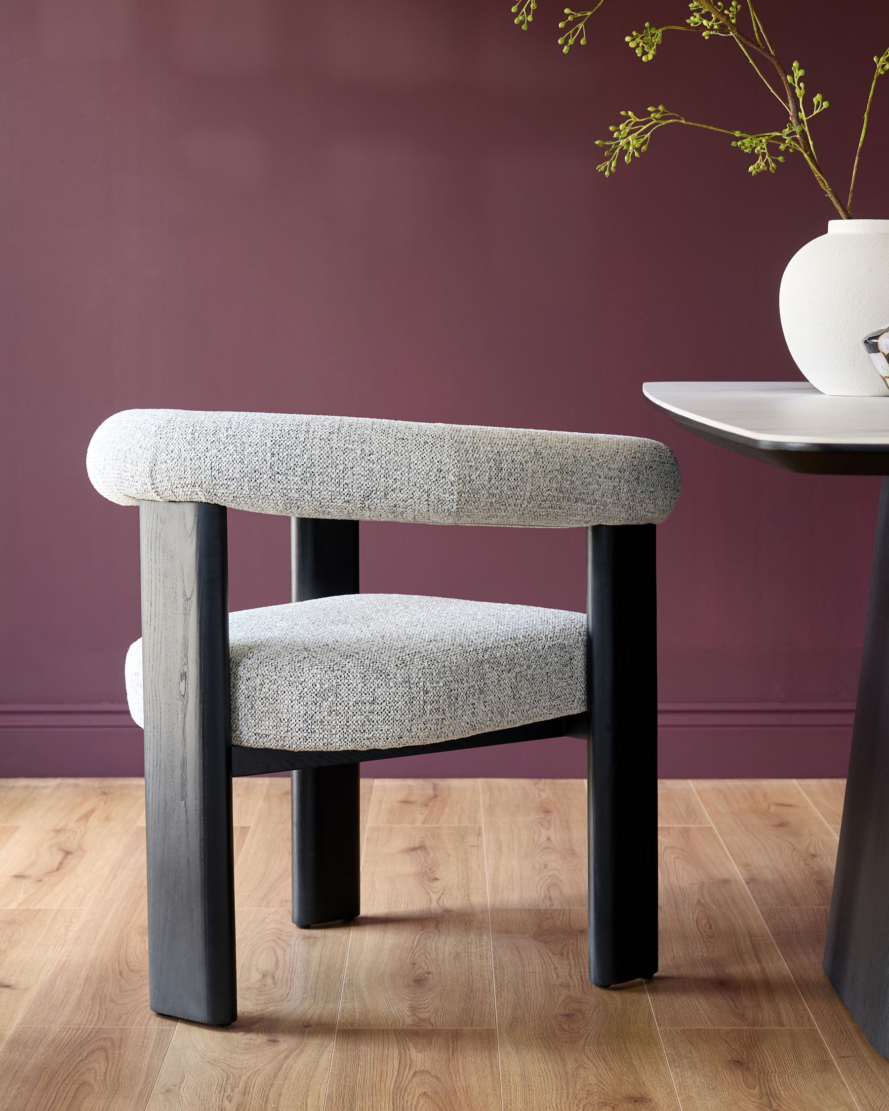 Stylish chair with grey tweed upholstery and dark wood legs. Sleek table with white top and dark base.