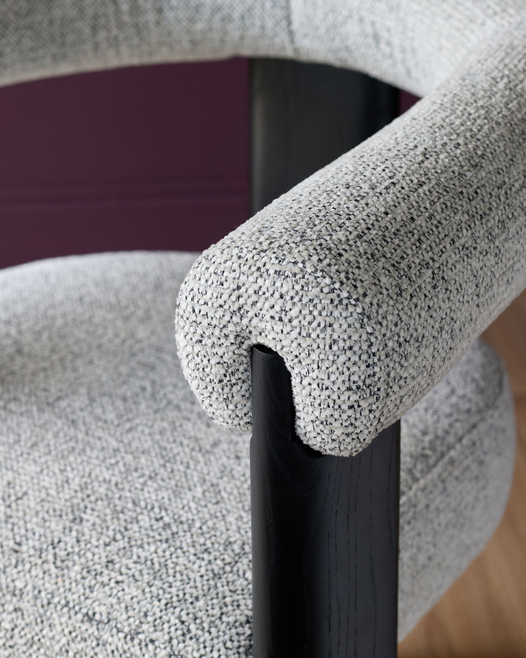 Close-up of a grey upholstered chair with a black wooden frame, showcasing its texture and design.