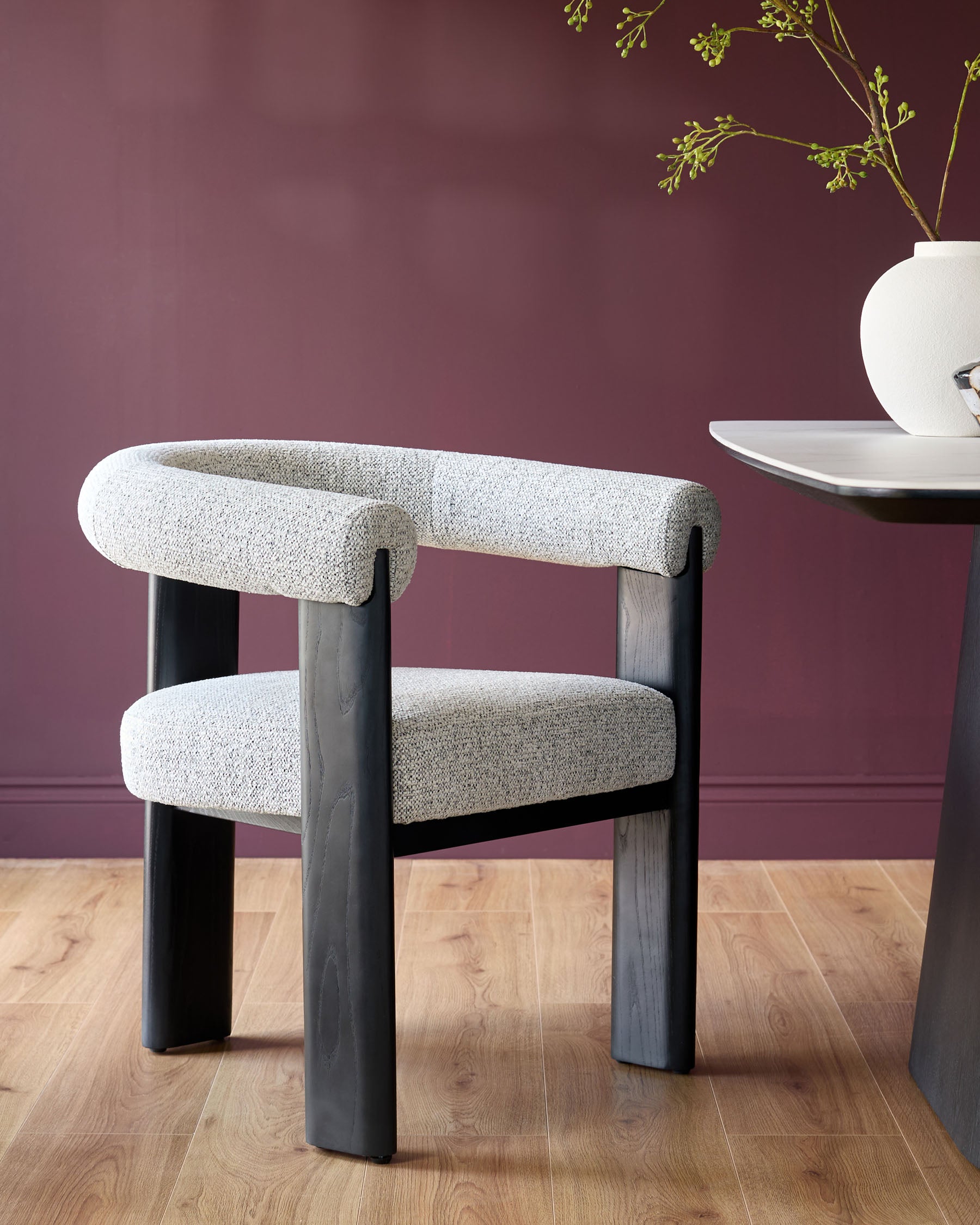 A modern chair with grey tweed upholstery and dark wood frame, sitting beside a sleek white table.