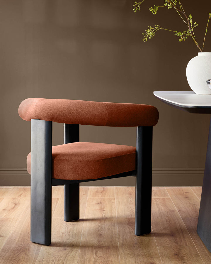Orion dining chair in toffee red fabric with black wooden legs, shown in a room setting on light wood flooring.