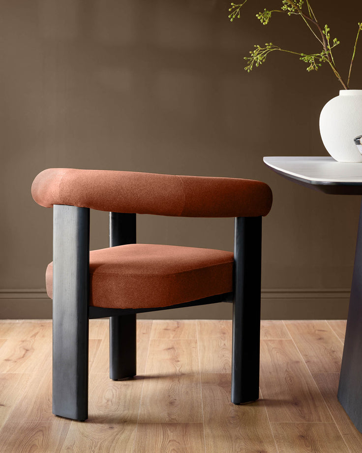 Orion dining chair in toffee red fabric with black wooden legs, shown in a room setting on light wood flooring.
