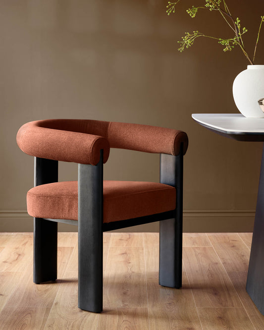 Orion dining chair in toffee-red fabric with dark wood legs, featuring a curved cylindrical backrest and seat cushion.
