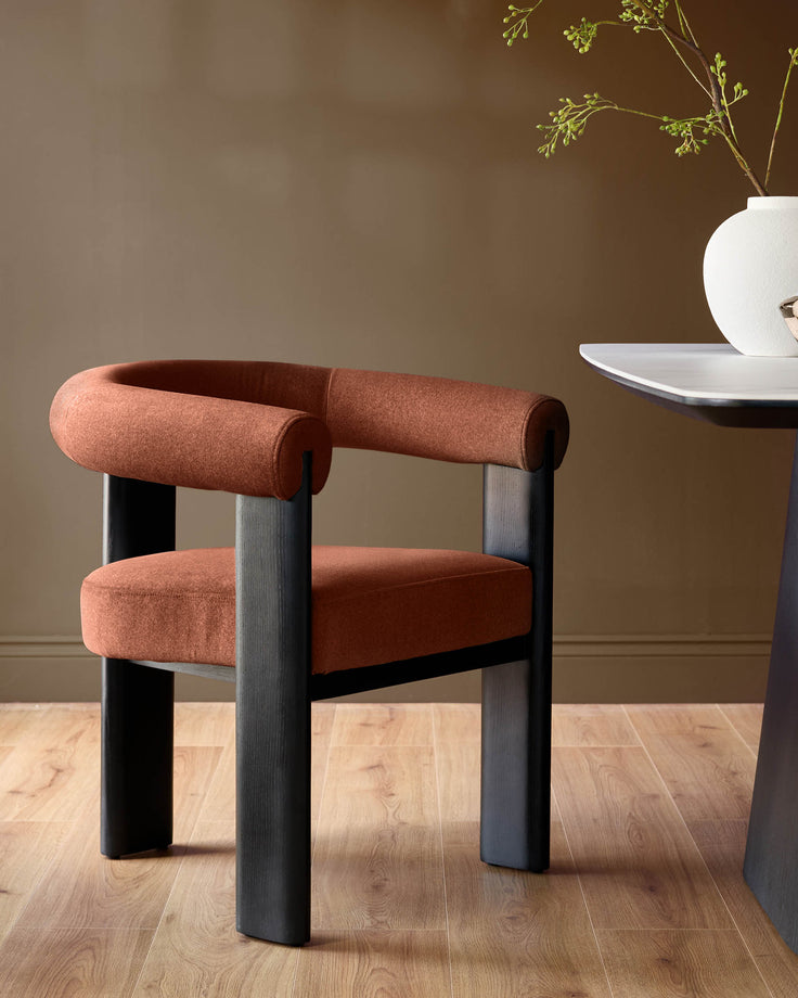 Orion dining chair in toffee-red fabric with dark wood legs, featuring a curved cylindrical backrest and seat cushion.