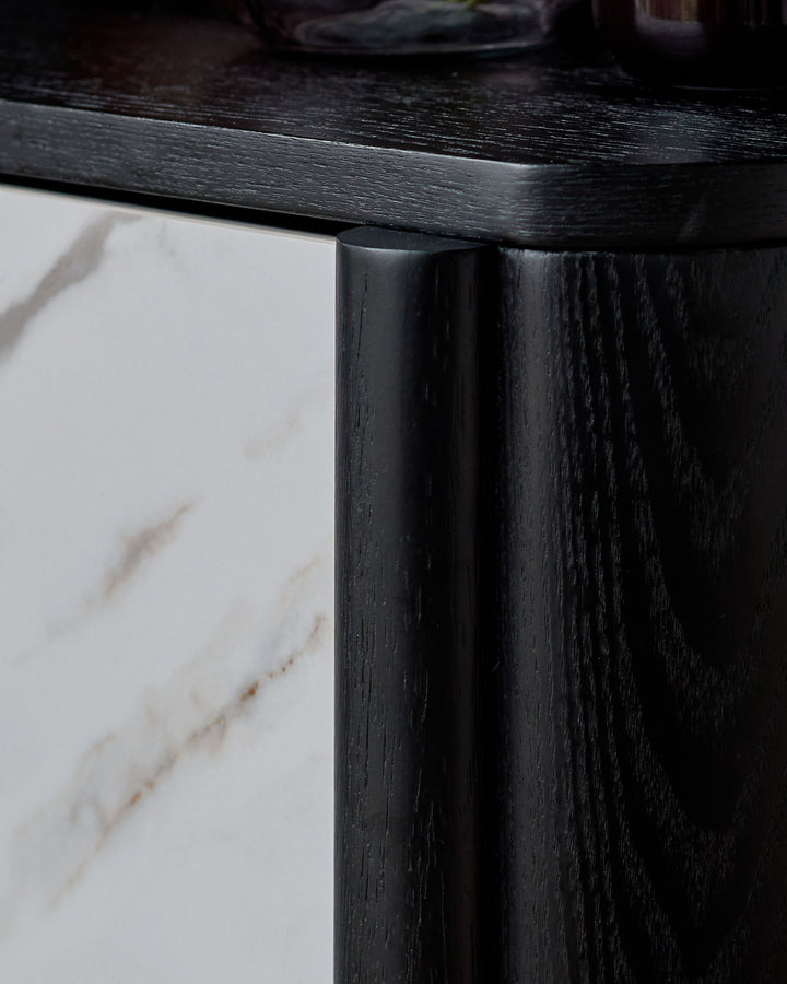 Black wooden bedside table with white marble top, close-up of leg and frame detail.