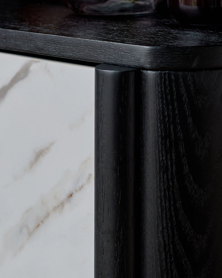 Black wooden bedside table with white marble top, close-up of leg and frame detail.