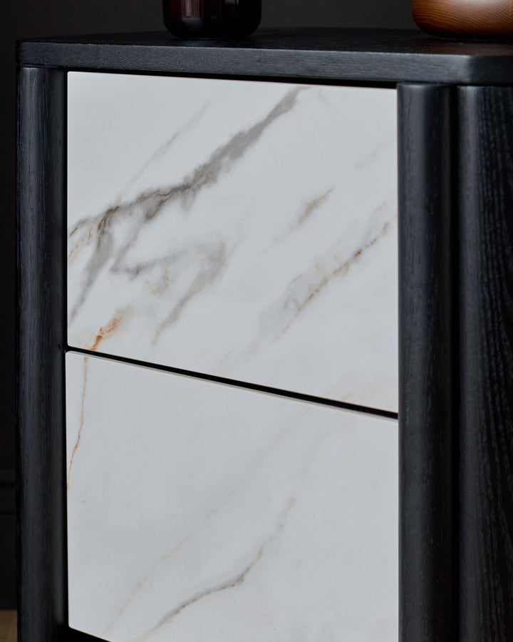 Orlan bedside table with black wooden frame and white marble top with natural veining, drawer front visible.