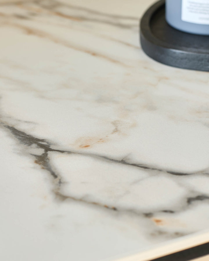 Close-up of a marble-effect table or counter top, featuring a grey decorative tray in the upper right corner.