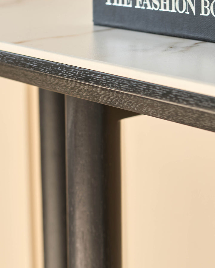 Close-up of a stylish side table with a faux marble top and sleek, dark-stained wooden frame and legs.