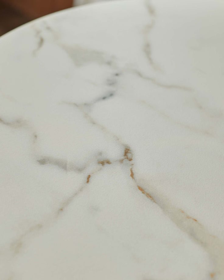 Close-up of a white marble table, showing the intricate veining and smooth surface. Perfect for a modern dining space.