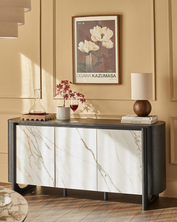 Stylish sideboard with faux marble doors, topped with a lamp, books, and a decorative arrangement.