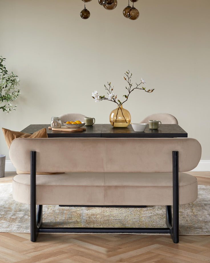 A stylish dining space with a dark wood table, beige bench, and decorative vase and tableware.