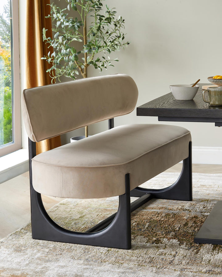 A stylish upholstered bench seat with a black frame. Part of a table and olive tree are also visible.