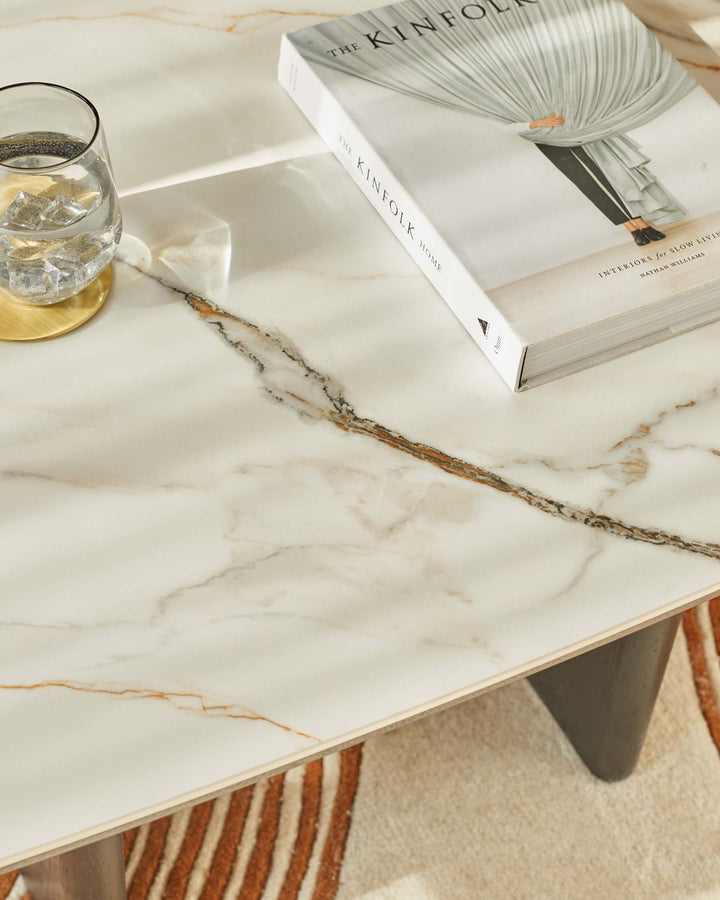 A marble coffee table, complemented by a glass of water and 'The Kinfolk Home' book, adding a touch of modern elegance to the room.