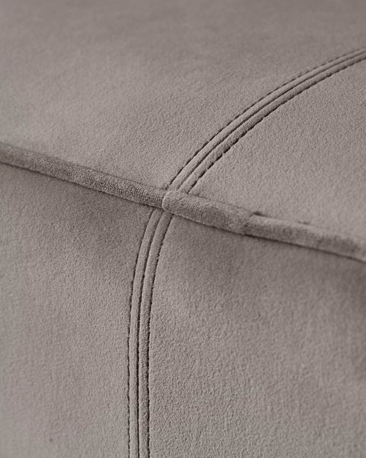 Close-up of a grey upholstered sofa with stitching detail. Shows the texture and plushness of the fabric.