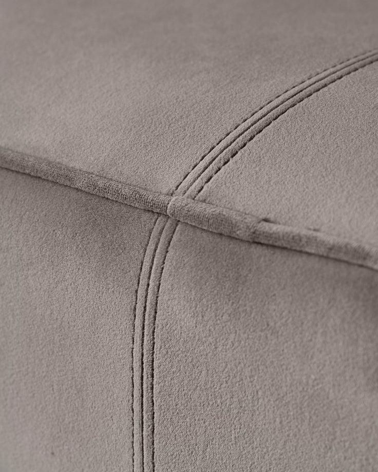 Close-up of a grey upholstered sofa with stitching detail. Shows the texture and plushness of the fabric.