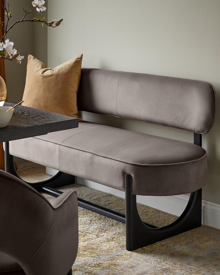 Stylish upholstered bench with a cushioned seat and back, on a black metal frame. Contemporary design.