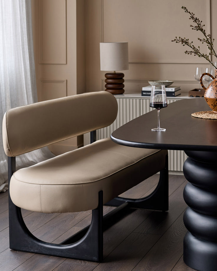 Orlan 3-seating dining bench with backrest in natural faux leather, black wood base, curved design, styled in modern interior.
