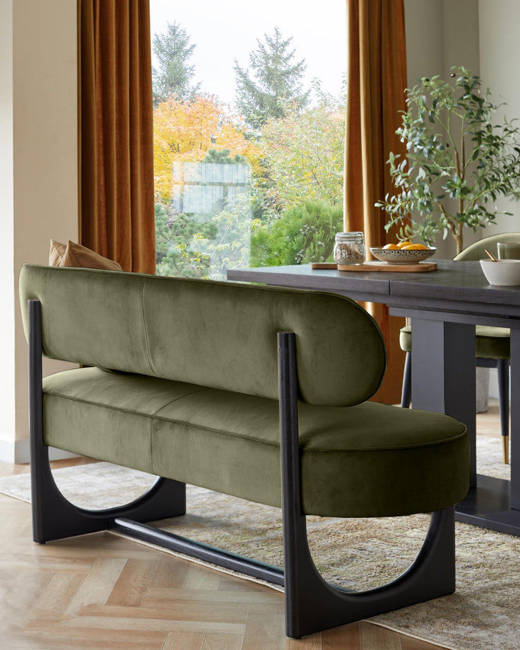 Orlan dining bench with backrest in olive green velvet, black wooden frame, positioned at desk in bright room with autumn garden view.