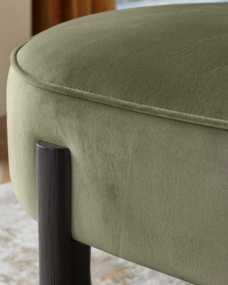 Orlan dining bench with backrest in olive green velvet, showing curved backrest and dark wooden leg detail.