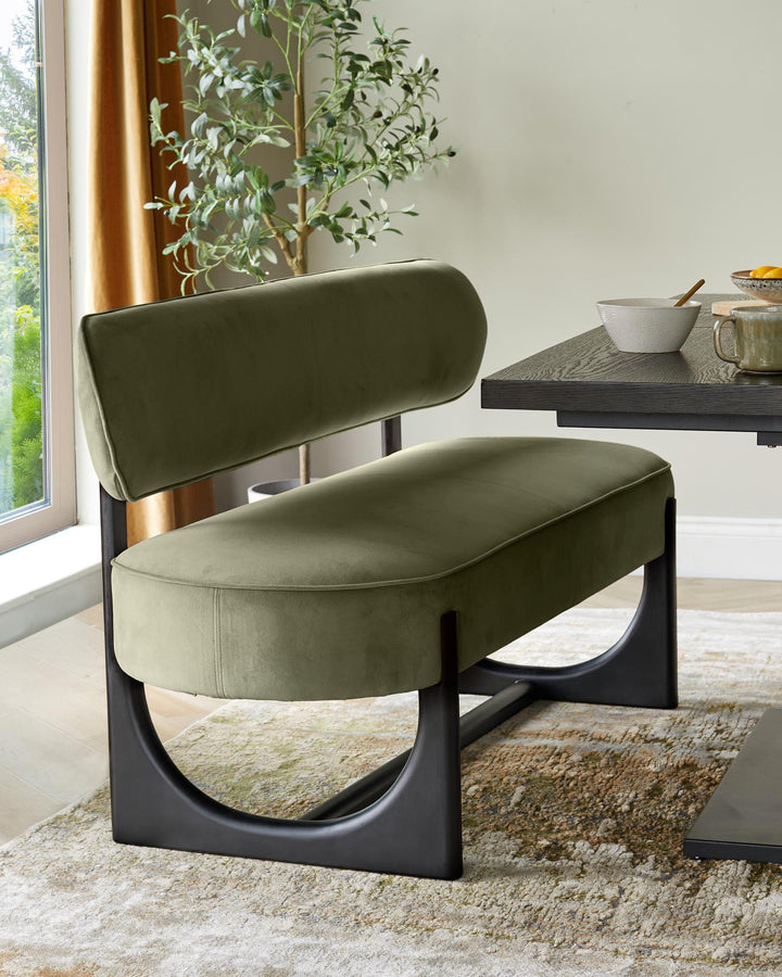 Orlan dining bench with backrest in olive green velvet, featuring a black sculptural base, positioned at a dining table.