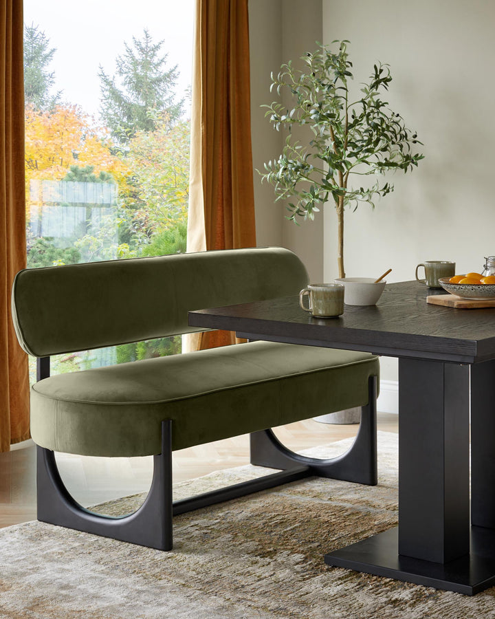 Orlan dining bench with backrest in olive green velvet, paired with black table in modern room setting.