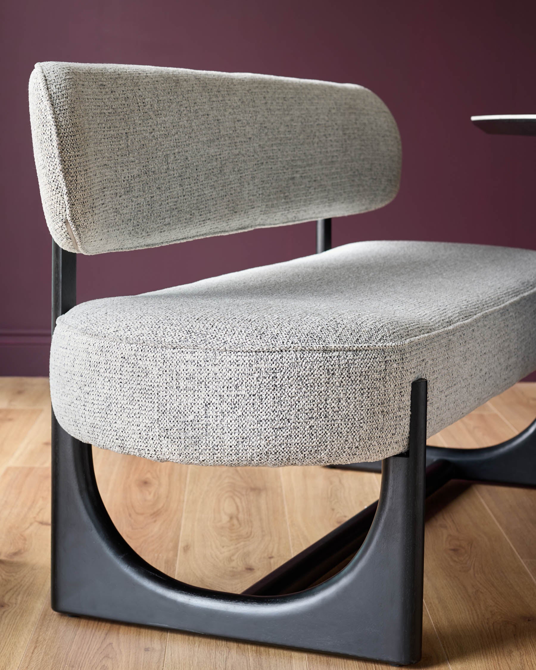 Stylish grey fabric chair with curved black frame, ideal for modern living rooms.
