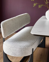 Stylish dining chair with curved upholstered seat and backrest, paired with a modern marble-look dining table.