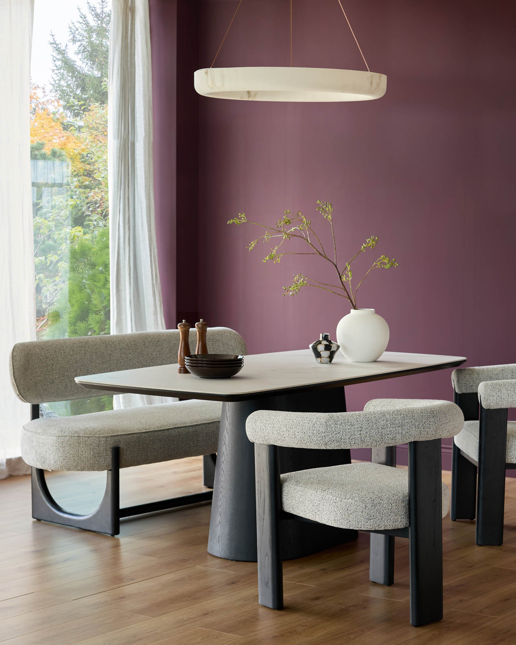 A modern dining set featuring a stone-topped table with a unique base, complemented by upholstered chairs and a bench.