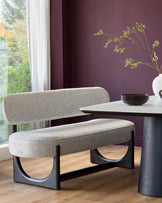 Upholstered dining bench with dark wood legs and a marble-look table with dark wood base. Contemporary style.