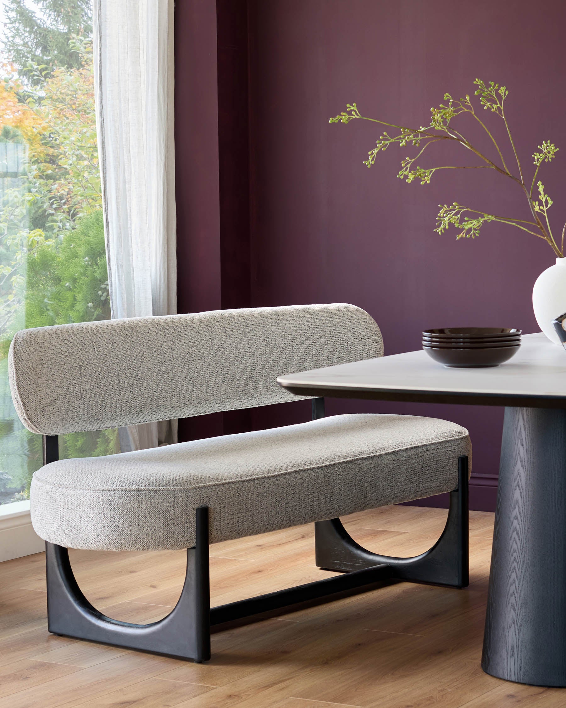Upholstered dining bench with dark wood legs and a marble-look table with dark wood base. Contemporary style.