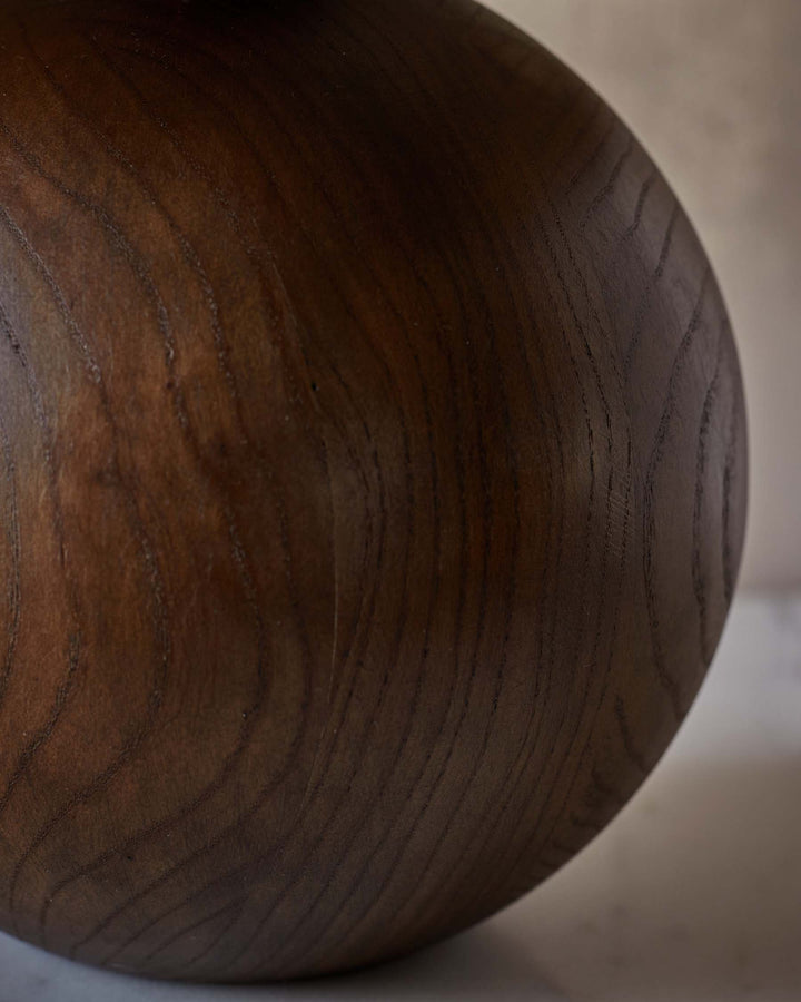 Close-up of a dark wood bowl, showcasing the natural grain and texture of the wood. Minimalist and organic design.