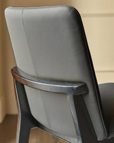 Otis dining chair in dark grey leather, side view showing curved backrest and dark wood frame detail.