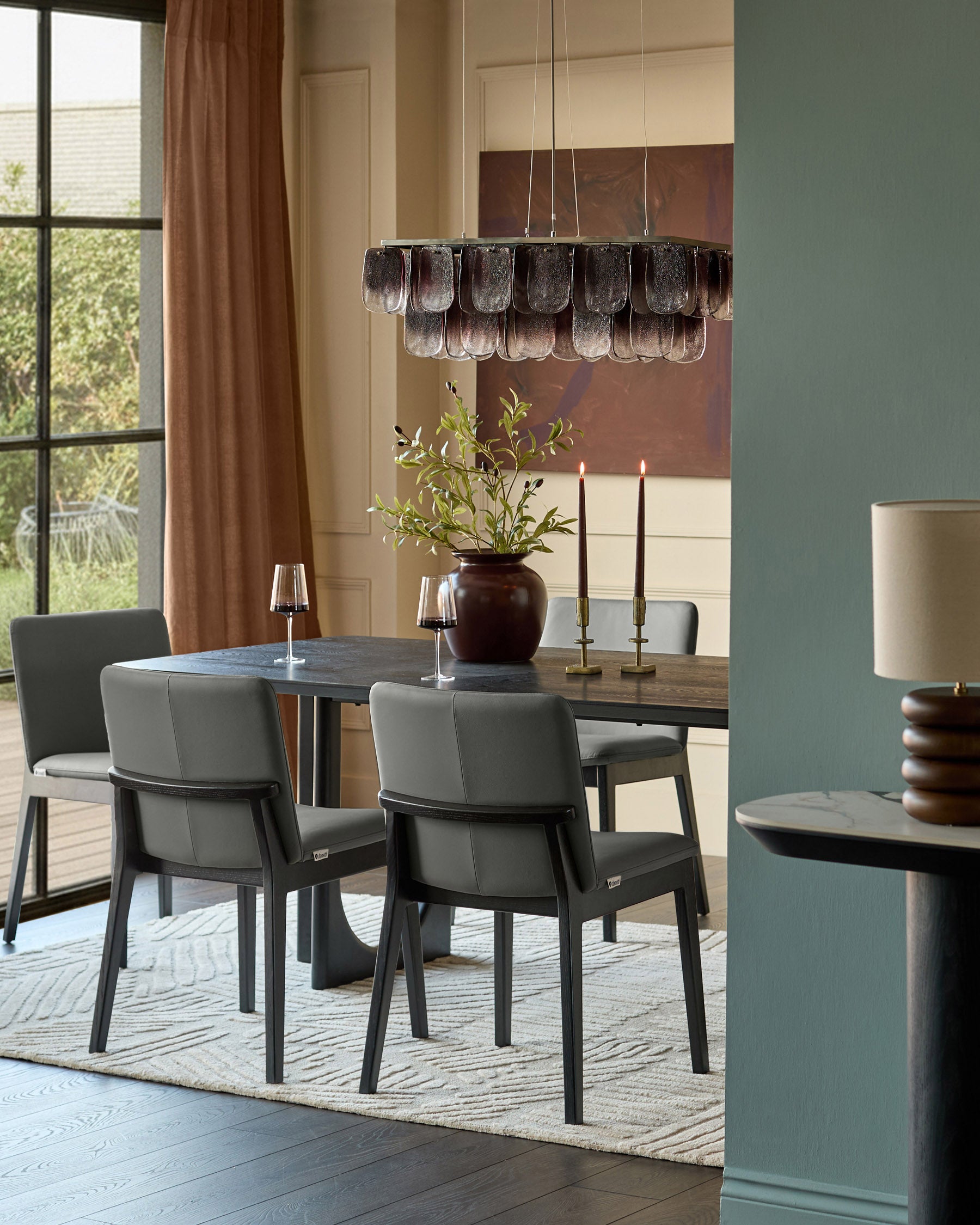 Otis dining chair in dark grey leather, shown as part of a dining set with table and pendant lighting.