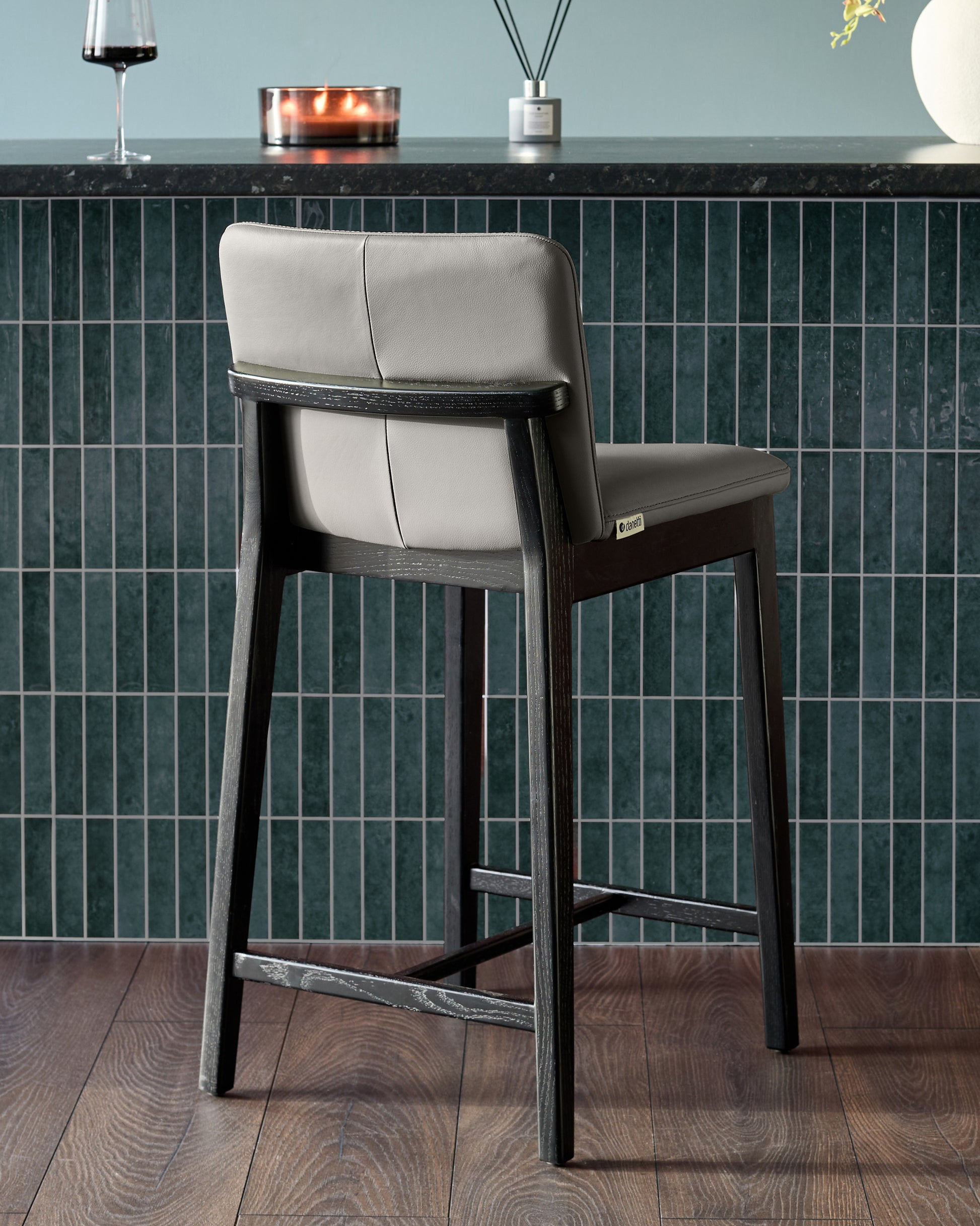 Otis bar stool in dark grey wood with cream leather seat and backrest, shown from rear angle at counter height.