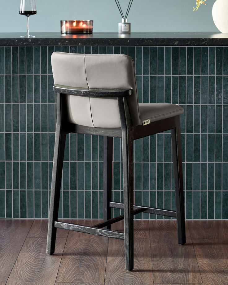 Otis bar stool in dark grey wood with cream leather seat and backrest, shown from rear angle at counter height.