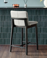 Otis bar stool in light grey leather with black wood frame, shown from rear angle at counter height.