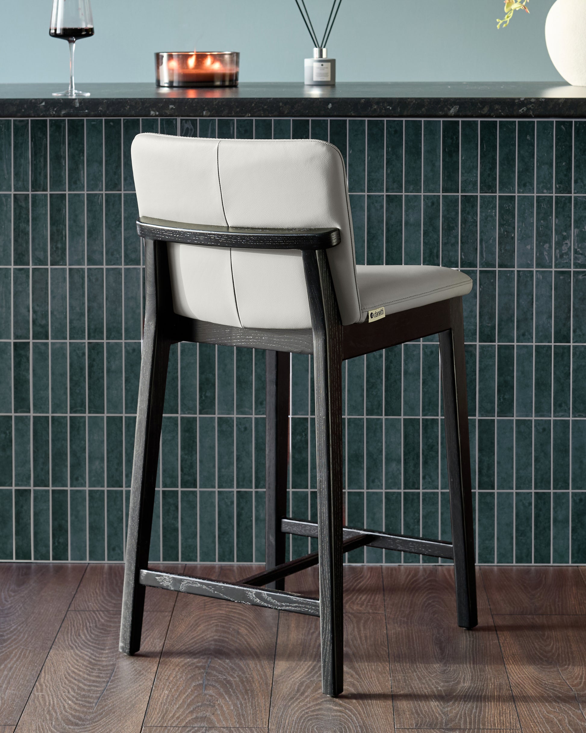 Otis bar stool in light grey leather with black wood frame, shown from rear angle at counter height.