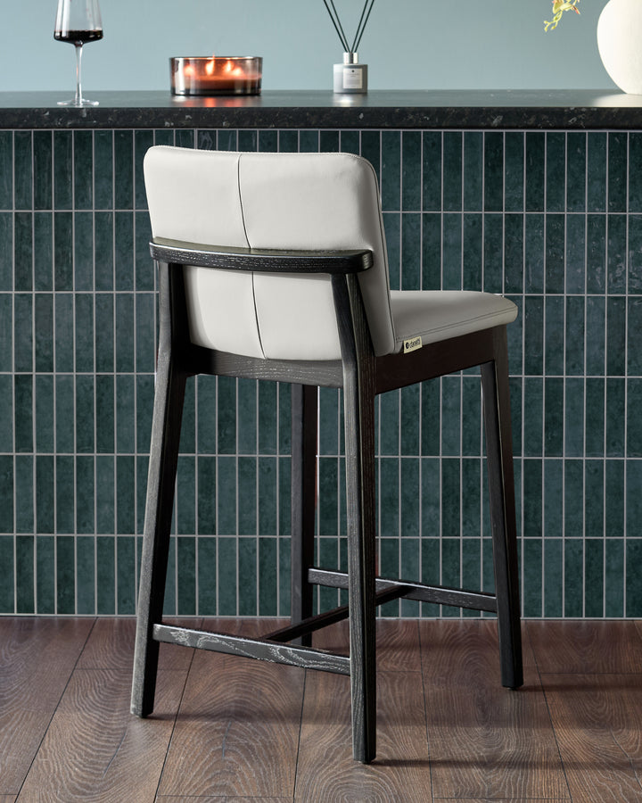 Otis bar stool in light grey leather with black wood frame, shown from rear angle at counter height.