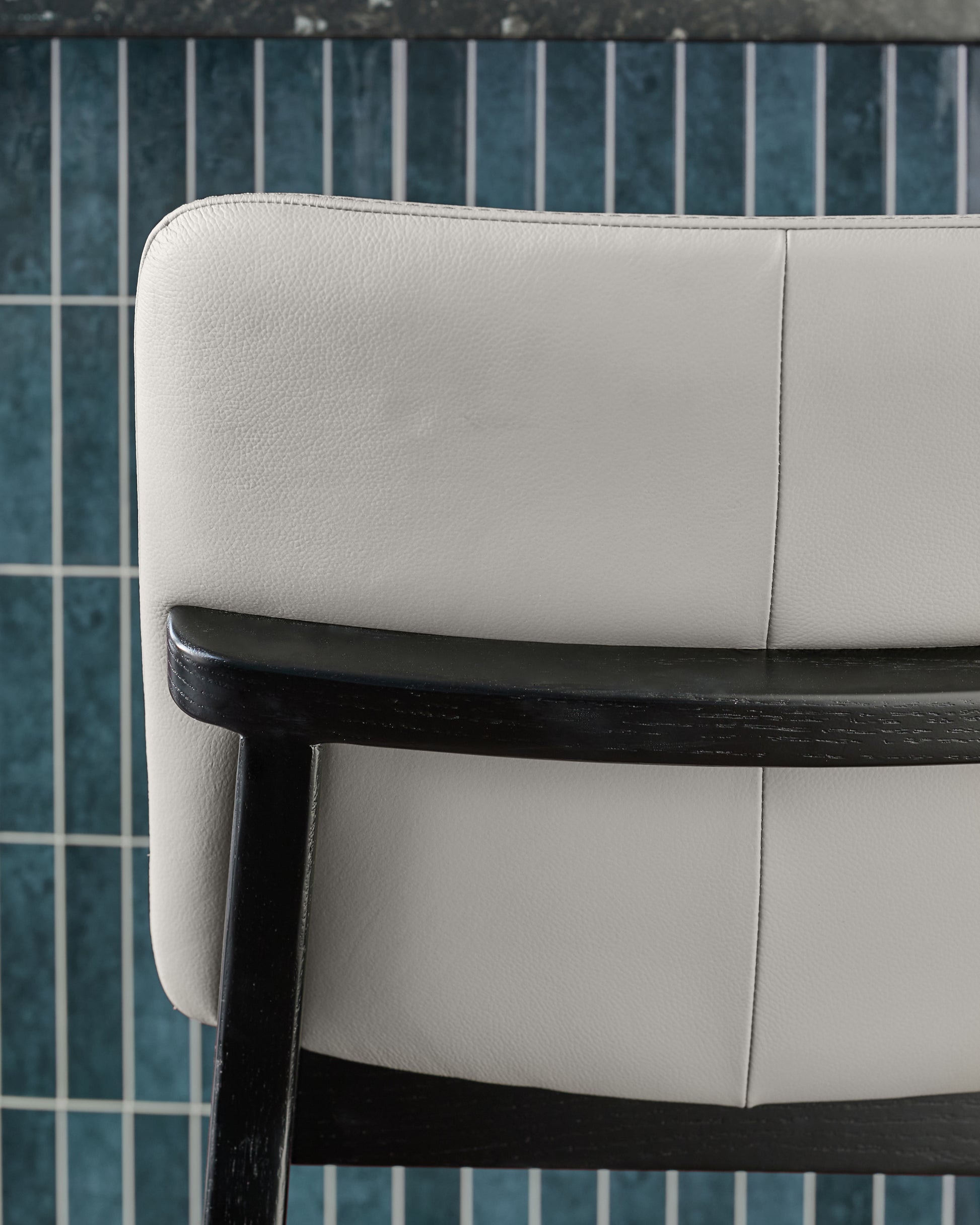 Otis bar stool in light grey leather with black wooden frame, shown in side angle detail view.